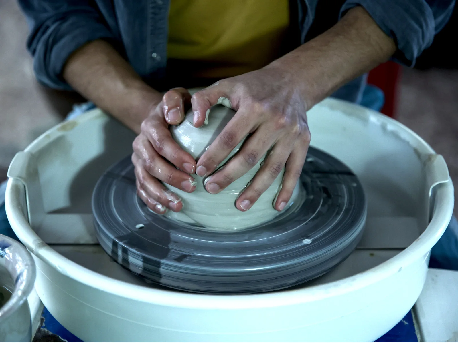 Potter's hands shaping clay on wheel